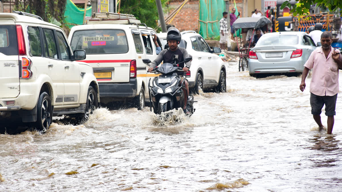 Vehicles wade through a waterlogged street after heavy rainfall in Satgaon, Guwahati, Assam, on Monday.