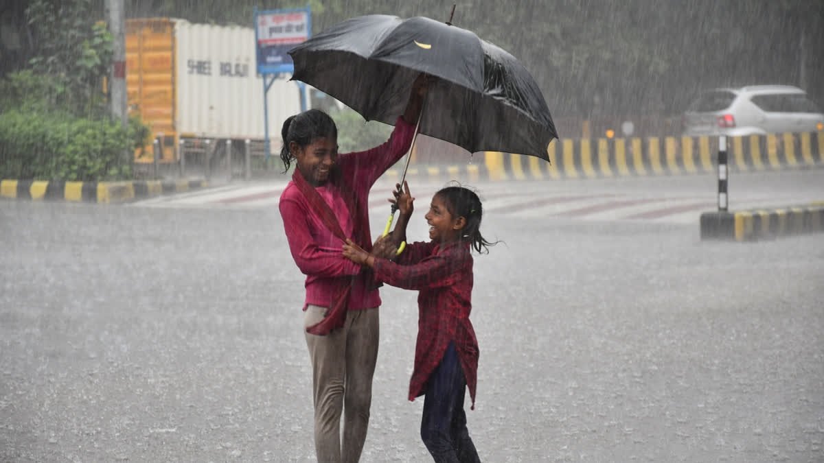 Two girls share an umbrella as they enjoy the rain, in Prayagraj, Monday, July 20, 2026.
