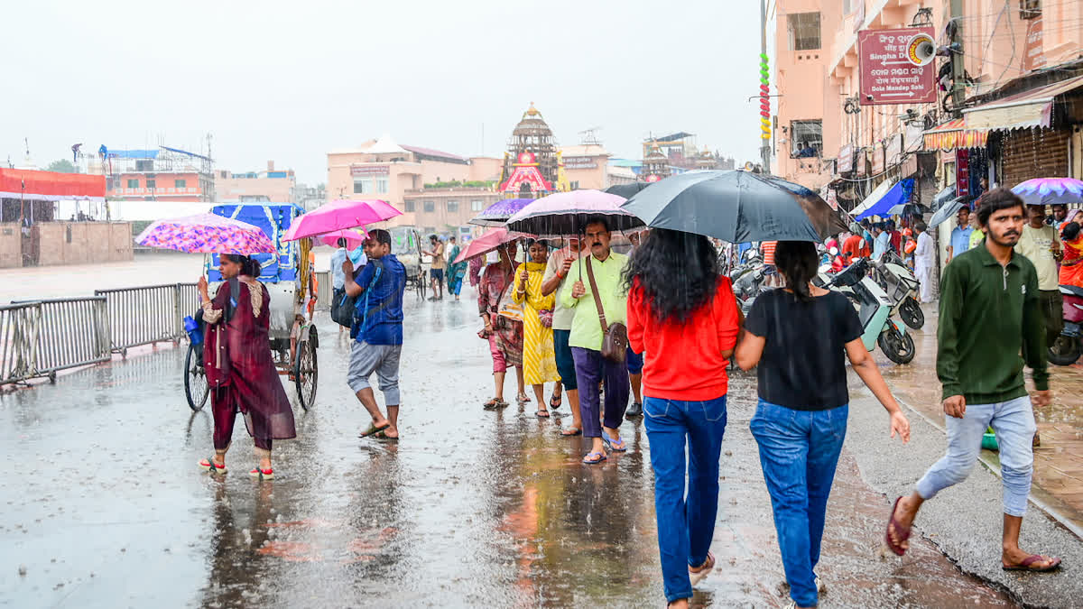 Devotees carrying umbrellas throng the Shri Jagannath Temple amid rain ahead of the annual Rath Yatra festival in Puri, Odisha, on Tuesday.
