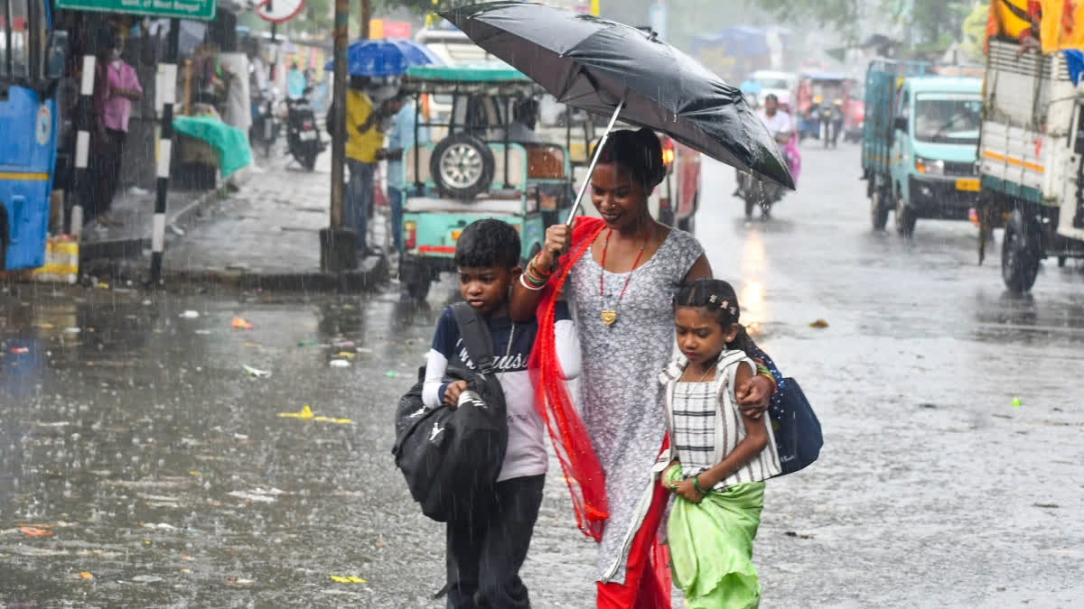 A woman walks with her children amid rainfall in Jalpaiguri district, West Bengal.