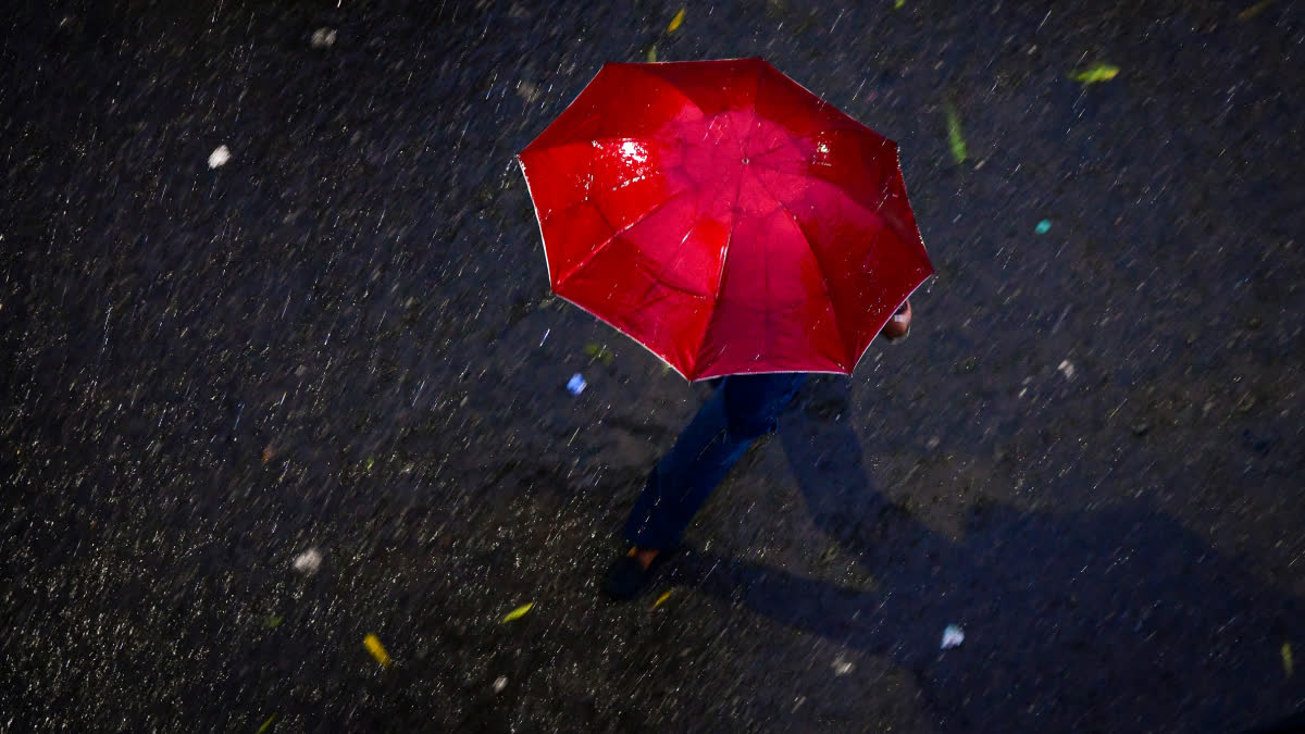 A man covers himself as he passes by amid rainfall, in Guwahati, Assam.